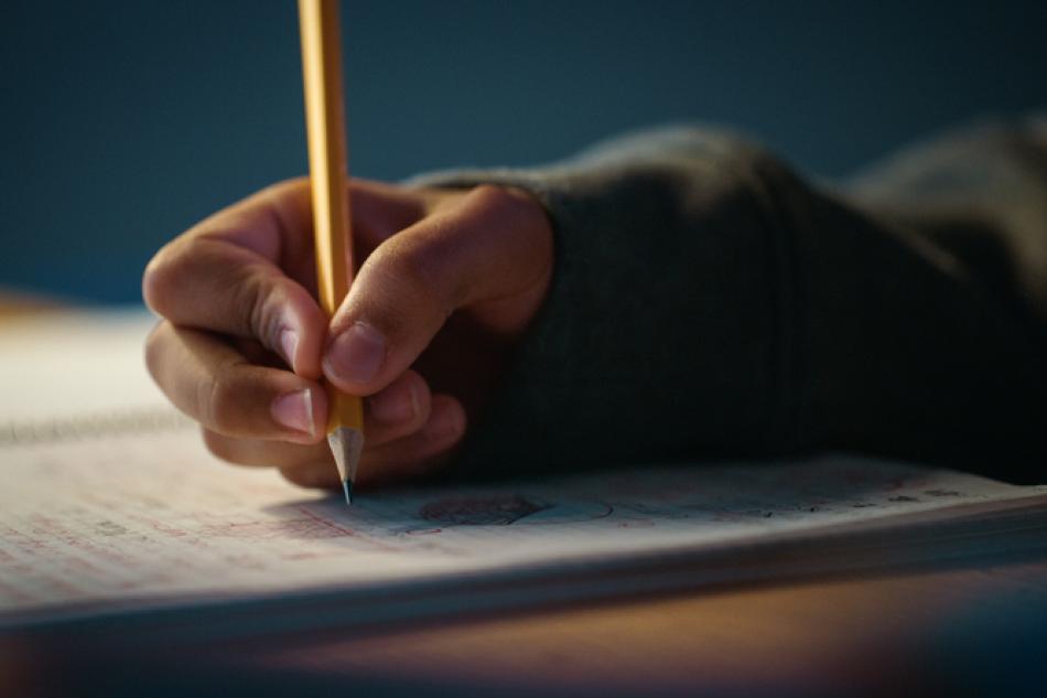 een rechterhand schrijft met potlood in een schrift