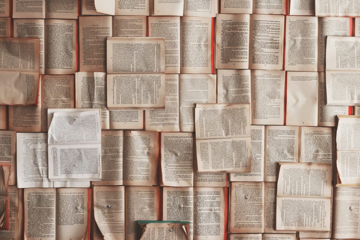 diverse opengeslagen boeken hangen op een wand.